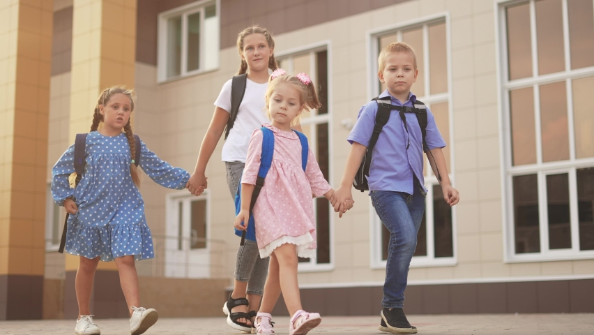 back to school. a group of schoolchildren with backpacks walk next to the school. education kids concept. schoolboy and schoolgirl going to school lifestyle. a group of children walking