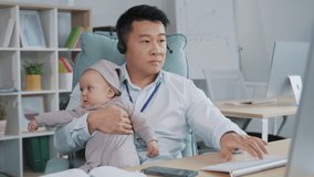 Young asian businessman working in office with a baby. Remote job, multi-tasking and family concept.