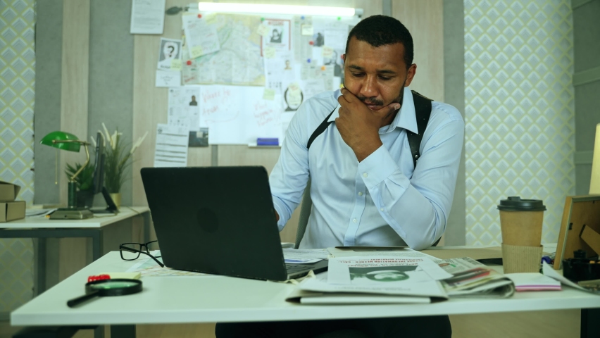 Focused policeman studing a missing girl poster.Sensible private detective thinking about missing person case, while leaning back in the chair and reviewing missing girl poster.High quality 4k