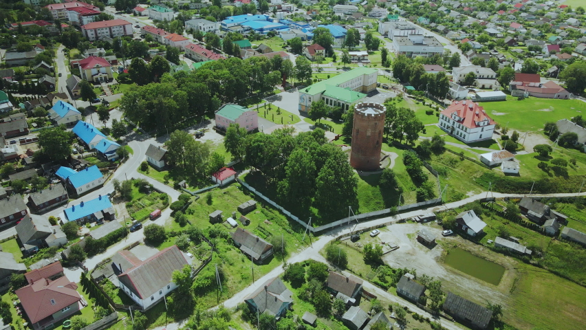 Flight over a provincial town. An ancient tower among the multi-colored roofs of houses. Aerial photography.