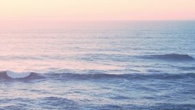 Beautiful Waves Breaking Ocean Seascape Background at Sunset with Sun Setting, Pastel Muted Warm Orange Colours from Elevated Aerial Drone View