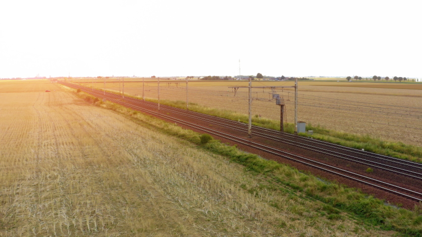 A high speed electric passenger train passes through the countryside of Normandy, France. high speed train between the fields, top view. High Speed Train from Sky.  Royalty-Free Stock Footage #1093127565