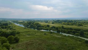  Top view of green fields, hills, trees and river bed. Landscape. Wildlife. Aerial video footage from a drone
