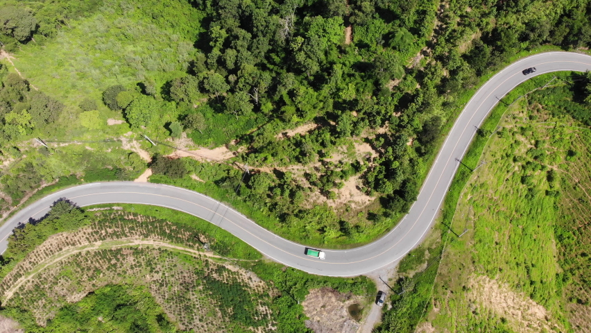 Aerial view of the road against the backdrop of green mountains along which the car is traveling. | Shutterstock HD Video #1093130533