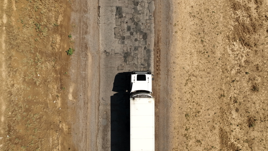 Aerial top view of semi-trailer white trucks with cargo moving across the desert in Karaganda Region, Kazakhstan. A small herd of horses grazing along the roadside. | Shutterstock HD Video #1093133399