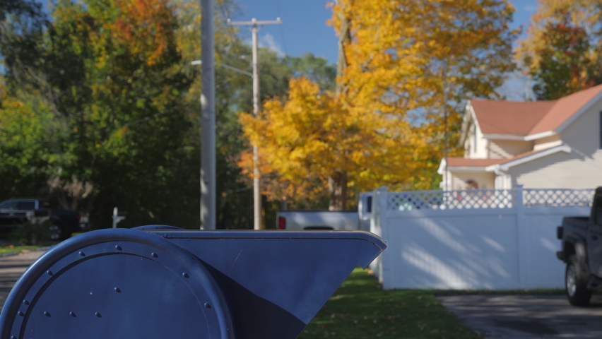 A child sends a letter - throws it into a blue mailbox on a typical American street