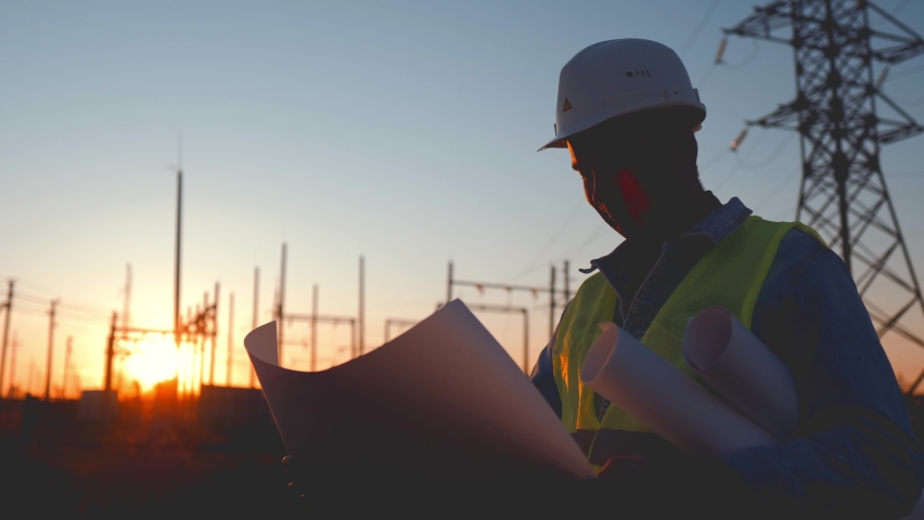 Foreman stands on construction site and holds drawings on paper in hands. Man shows hand where future construction be according to plan. Field with telecommunications tower. Male in protective helmet | Shutterstock HD Video #1093142183