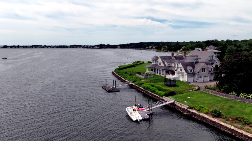 An aerial view of a beautiful house at Stony Point on the banks of the Saugatuck River in Westport Connecticut. Shot on a cloudy day, the drone camera dolly in and truck left orbiting the large house.