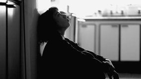 Grainy clip of Person suffering from mental illness sitting on floor at home in monochrome. Girl struggling with depression in black and white photography with noise