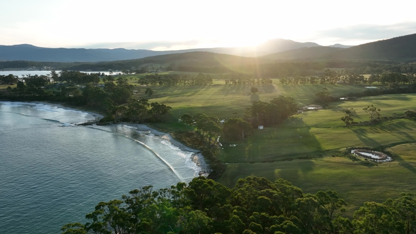 Farm next to the ocean and beach. Ranch with water views. Beautiful coastal scenery with cows and cattle in evening light at sunset in Australia 