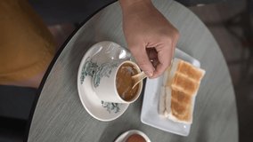 Man stirring hot coffee, having breakfast in a cafe. 