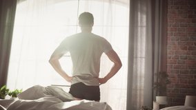Handsome Young Man Waking up in the Morning, Stretches and Gets Out of Bed, Sun Shines From the Apartment Window in Bedroom, He is Ready for Business Opportunities, Achievements, Adventures - Powered by Shutterstock - Get 15% off with code: PIKWIZARD15
