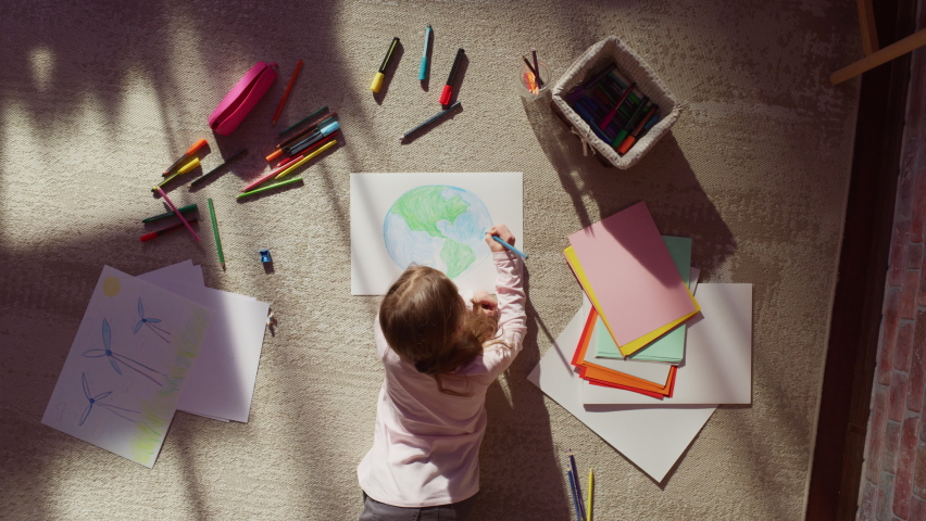 Top View: Little Girl Drawing Our Beautiful Planet Earth. Very Talented Child Having Fun at Home on the Floor, Imagining Our Home Planet as a Happy Place with Clean, Sustainable Living. Cozy Sunny Day Royalty-Free Stock Footage #1093149759