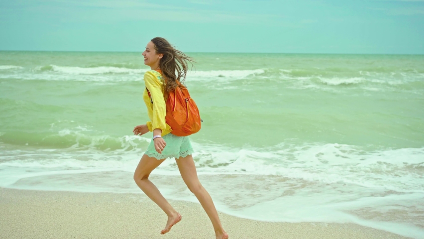 Happy woman enjoing running on sandy beach at windy stormy day, waving sea. Getaway dream concept. Freedom summer girl enjoying majestic seascape, beautiful nature view | Shutterstock HD Video #1093150455