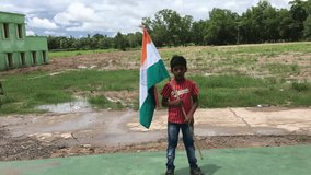 Cute little indian Boy holding, waving or running with Tricolour Indian Flag with natural background, celebrating Independence or Republic day