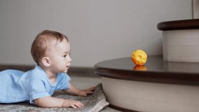 Little lovely kid interested by the toy crawls up to the stairs. Baby boy reaches a ball and bangs it by the stair happily. - Powered by Shutterstock - Get 15% off with code: PIKWIZARD15