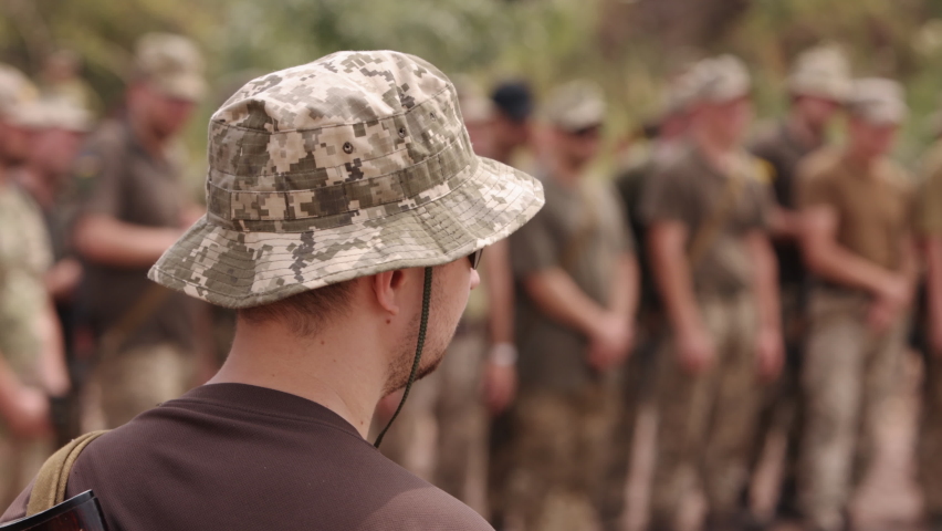 Ukrainian soldiers stand at the checkpoint, dressed in military uniforms, with Kalashnikov rifles behind their backs, close up