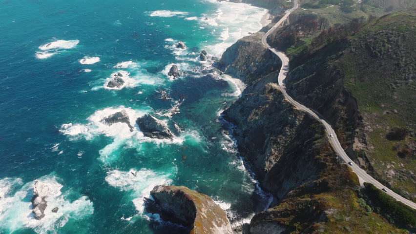 Pacific Ocean washes onto the beautiful seashore of California, on Monterey coast. Pacific Coast Highway runs by Big Sur nature park, along incredibly scenic coast with sea rocks and powerful waves Royalty-Free Stock Footage #1093172595