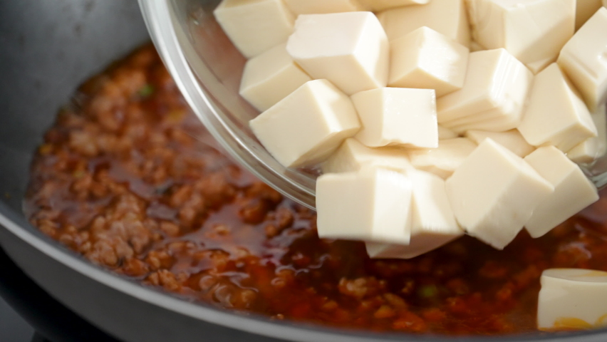 Cooking Mapo tofu. Homemade stir-frying tofu with hot spicy sauce in a pot at home.