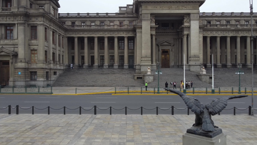Drone video of the Supreme court of justice of Peru, in capital city of Lima. Called "Palacio de Justicia". Drone flies slowly left to right, low to the ground. Passing a statue of a condor.