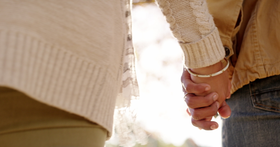 Walking, holding hands and in love couple relaxing on romantic park or garden date and showing support, unity and affection. Closeup of loving, caring and affectionate man and woman bonding together