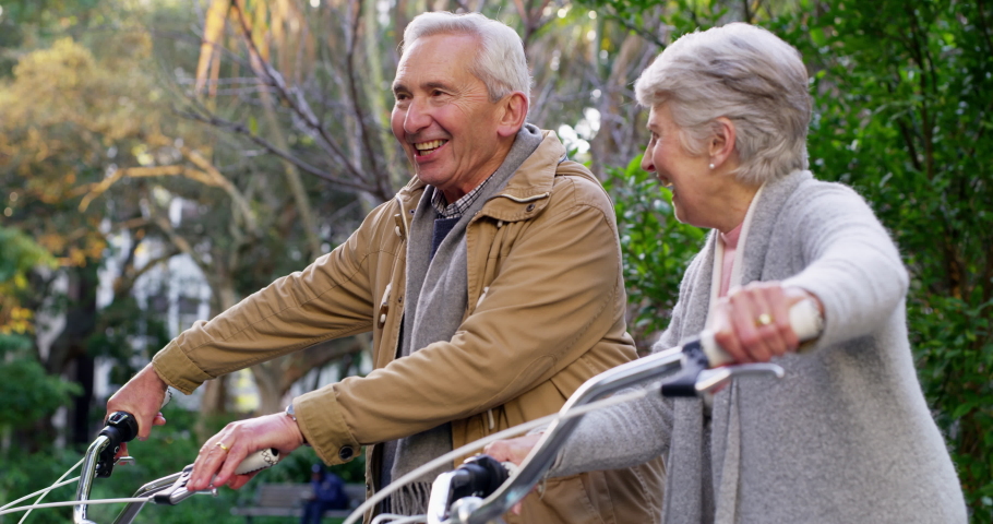 Happy, fun and mature couple talking while walking in a park together, happy and excited to go on a bike ride outdoors. Active seniors enjoying healthy activities while bonding and being cheerful Royalty-Free Stock Footage #1093177033