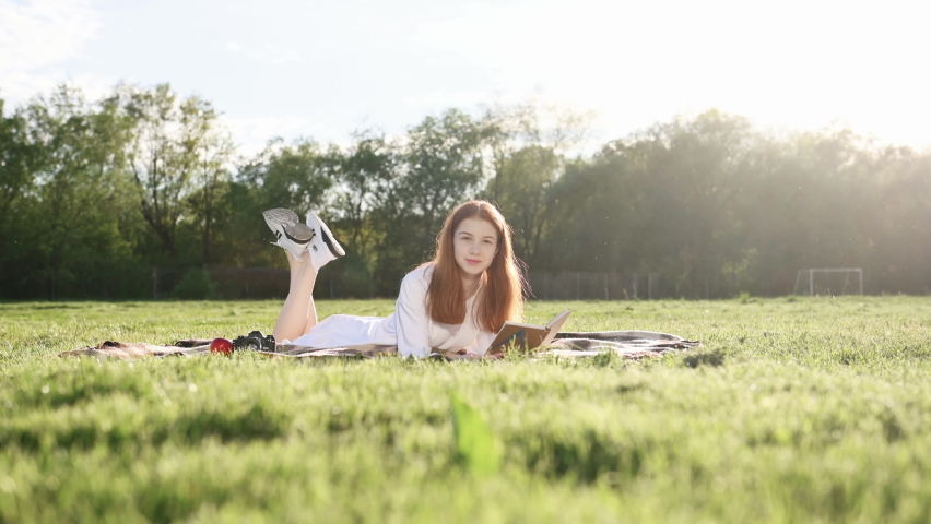 Reading the book. Young teenager laying down on the field at summer.
