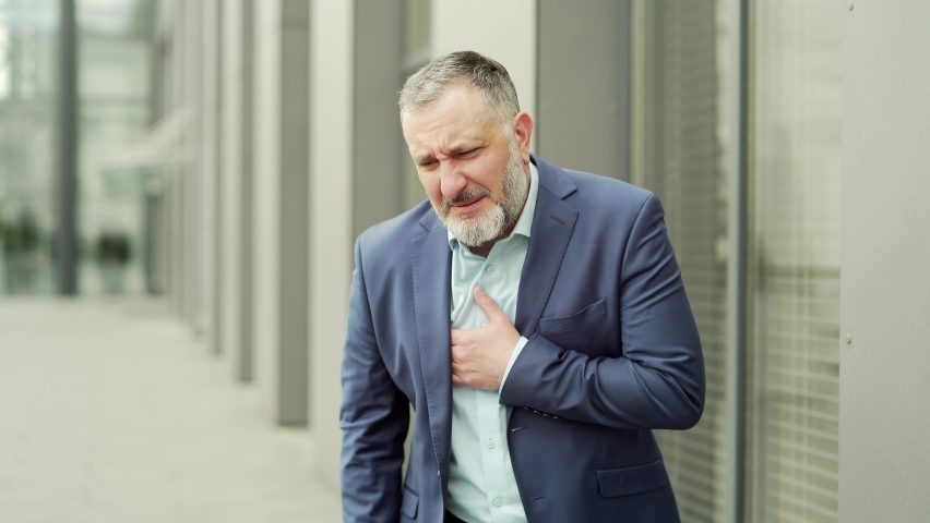 Mature business man with a sudden heartache is standing on a city street near office building. Senior businessman, employee holding chest outside outdoor feeling sharp chest pain, symptom heart attack | Shutterstock HD Video #1093180021