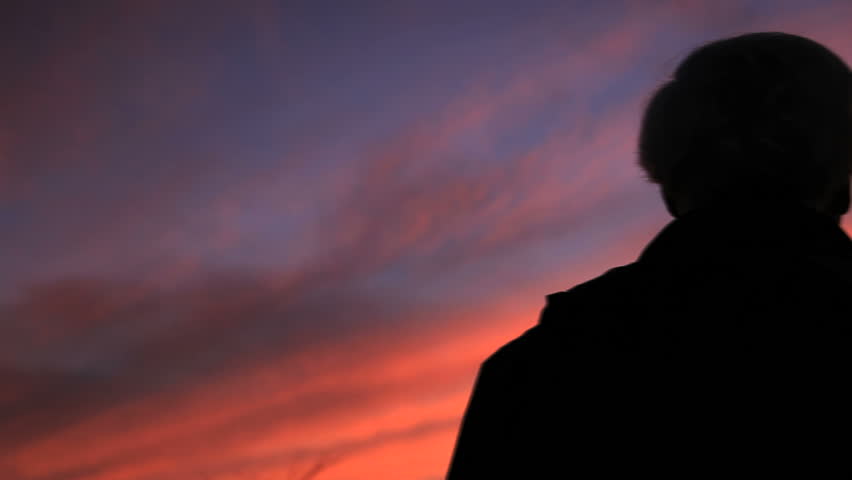 A man watching the sunset. Camera dollies across him.