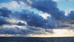 Timelapse with Sunset and Cumulus Clouds Flying High in a Beautiful Blue Sky. Sun Dawn over the Sea. Weather, Climate Change and Global Warming .