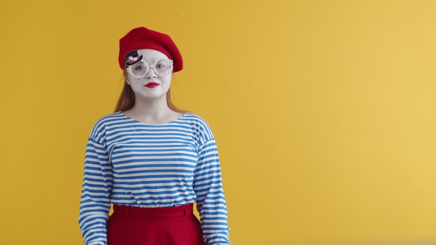 Actress mime talks to her hand as if on phone and shows OK gesture to the camera, on an orange background. Pantomime of talking phone, the concept of communication | Shutterstock HD Video #1093183915