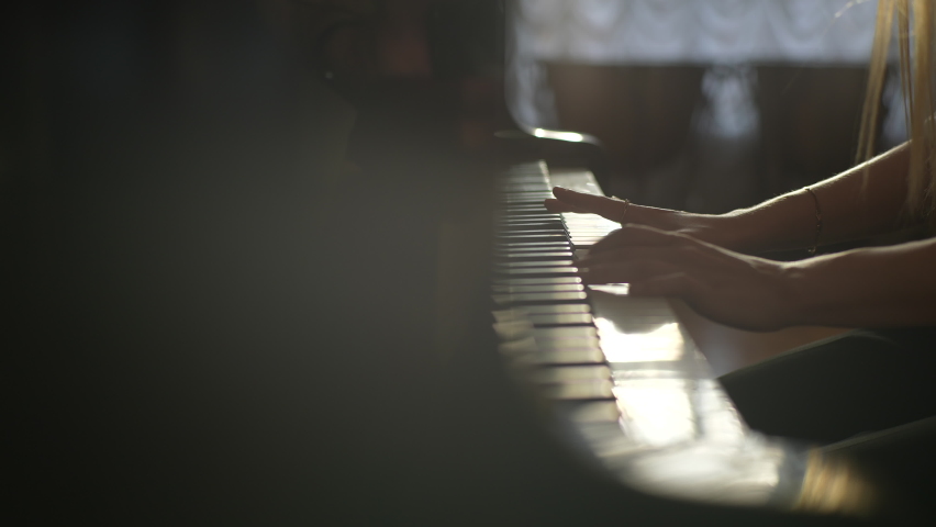 Close-up hands of unrecognizable young woman pianist playing energetic music on beautiful grand piano on background of window and bright sun rays. Tracking shot in slow motion. Royalty-Free Stock Footage #1093186097