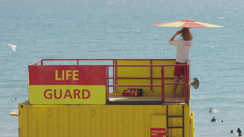 Lone lifeguard using binoculars to check on people playing in the sea