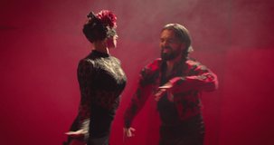 4k Beautiful couple dancing latin dance . Professional dancers dancing flamenco, rumba or salsa on red background. Couple in spanish dress performs dance movement. Shot ARRI ALEXA Cinema Camera .