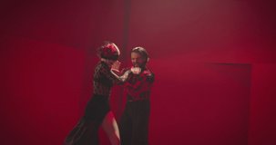 Beautiful couple dancing latin dance . Professional dancers dancing flamenco, rumba or salsa on red background. Couple in spanish dress performs dance movement. Shot ARRI ALEXA Cinema Camera .