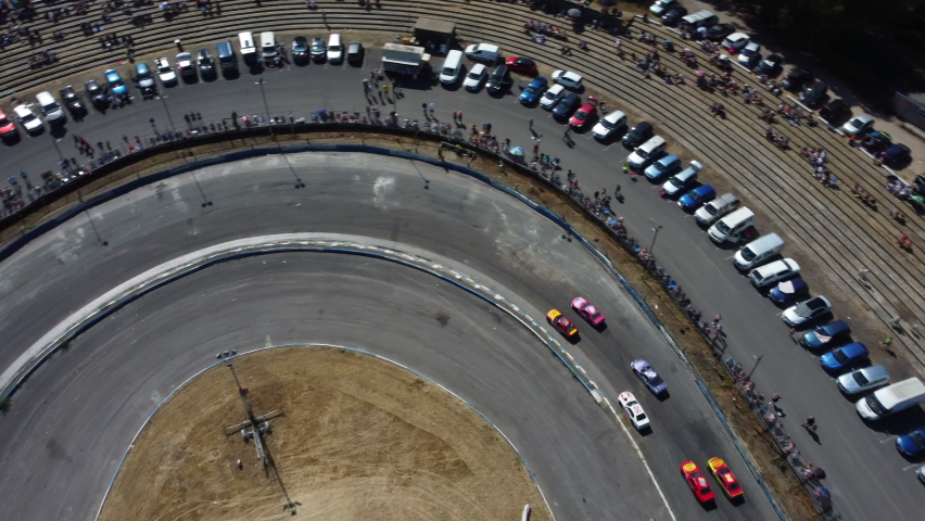 race cars racing around an oval circuit from above