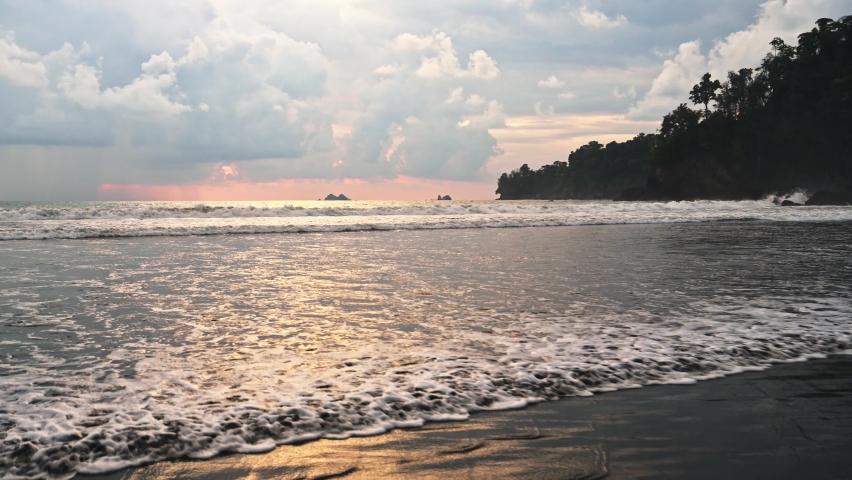 Costa Rica Beach Landscape at Sunset on Pacific Coast at Playa Ventanas by Ballena Marine National Park (Marino Ballena), Coastal Scenery with Dramatic Sunset Clouds and Waves, Central America Royalty-Free Stock Footage #1093199823