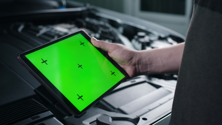 Unrecognizable male car service worker checking car and doing maintenance using a digital tablet computer with green screen chromakey, while standing near the opened bonnet | Shutterstock HD Video #1093200229