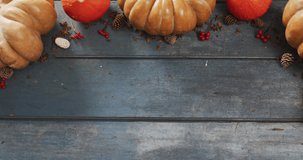 Video of pumpkins with pinecones and rowanberries on wooden background. Halloween, autumn, tradition and celebration concept.