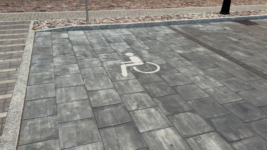 City disabled parking lot white sign over brick pavement