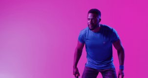 Video of successful african american male tennis player hitting ball on neon pink lightning. Sport, movement, fitness and active lifestyle concept.