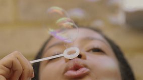 Low angle of young girl blowing bubbles as they fall and float around, in slow motion  - Powered by Shutterstock - Get 15% off with code: PIKWIZARD15