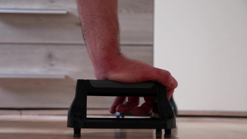 Sportive man training push-ups at home shows muscular man with trained triceps and strong arms healthy fitness trainer excercising with bodyweight as home workout in apartment with adult bare feet