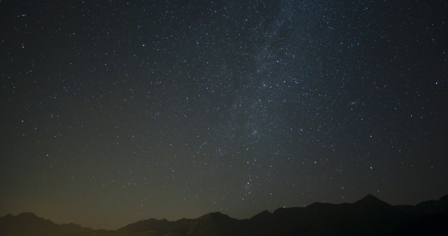 Timelapse of silhouetted mountains with circumpolar star trails in northern sky