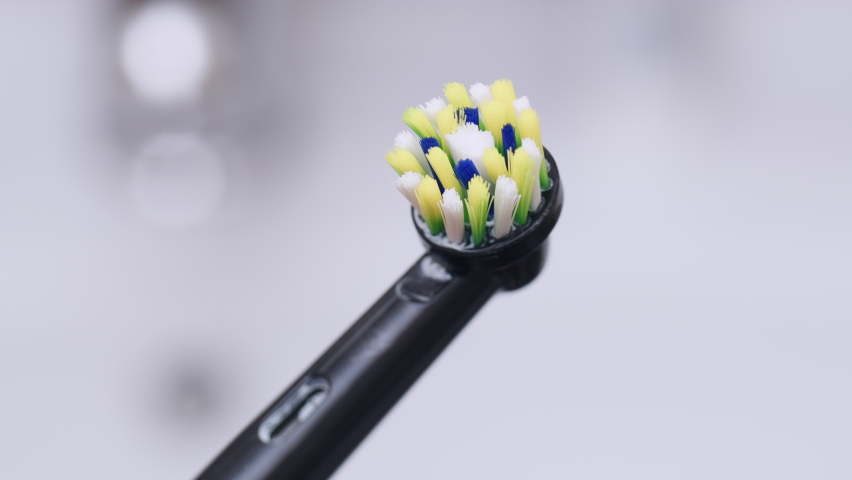 Rotating worn out bristles of electric toothbrush. View of old ultrasonic tooth brush head in bathroom. Smart black toothbrush with colorful bristles for oral hygiene and cavity prevention. Royalty-Free Stock Footage #1093215027