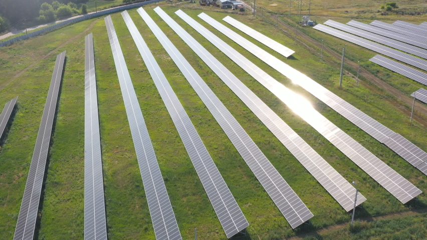 Rows of solar panels installed on field. Aerial shot of solar power station which generate renewable green energy. Sun reflection on solar panel surface. Production of clean ecological energy. Closeup | Shutterstock HD Video #1093219309