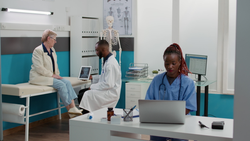 Health specialist analyzing x ray scan on digital tablet with senior patient, talking about bones radiography results. Doing diagnosis examination at medical appointment in healthcare clinic. | Shutterstock HD Video #1093219423