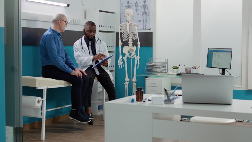 African american doctor consulting senior man with disease, giving prescription medicine and treatment to cure diagnosis. Physician and patient talking about healthcare support in cabinet. | Shutterstock HD Video #1093219449