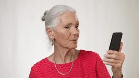 Portrait of smiling mature elderly woman posing holding phone video chat isolated on solid white background.