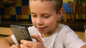 A boy of 6-7 years old plays a game on a gadget. Communication with the help of social networks. Kids end Gadgets. Concept of online distance learning